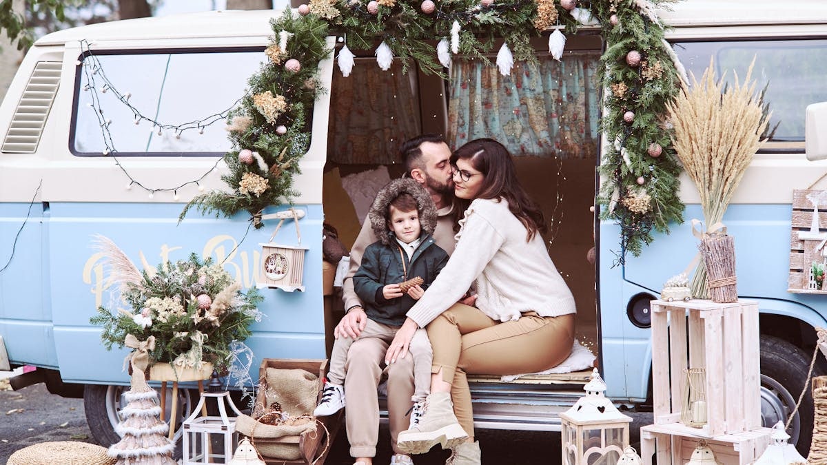 A family enjoys a festive moment in front of a beautifully decorated van.