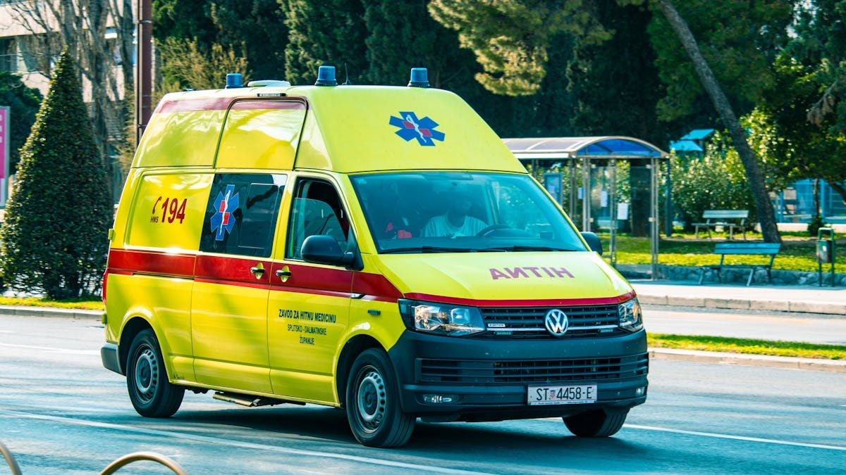 A bright yellow ambulance moves swiftly on a city street, providing emergency services.